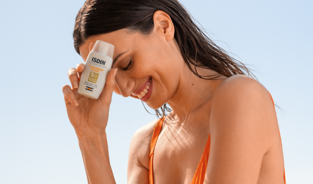 mujer sujetando protector solar de isdin
